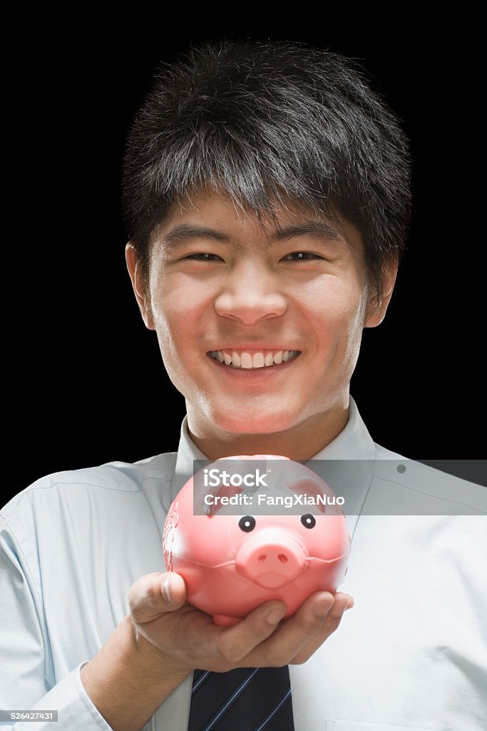 Businessman holding piggy bank, smiling, portrait Adult Stock Photo