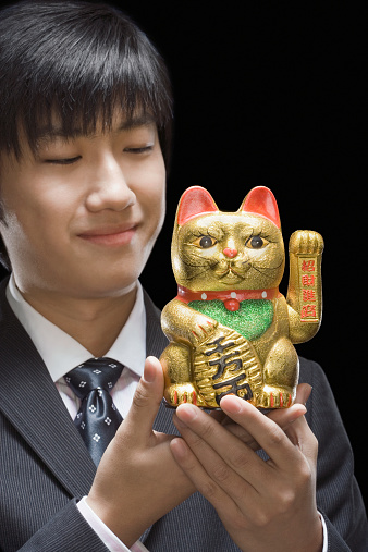 Businessman holding sculpture of traditional fortune cat Maneki Neko