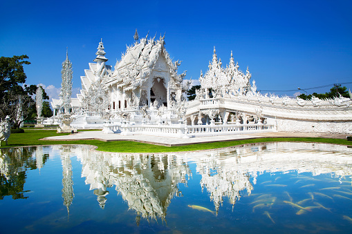 People stand at Phra Thinang Dusit Maha Prasat throne hall building, part of the Grand Palace in Bangkok, Thailand, on a cloudy day.