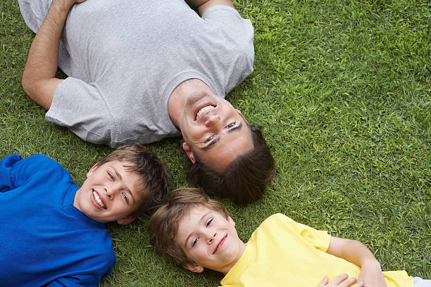 istock Happy Father And Two Sons Lying On Grass 526443527