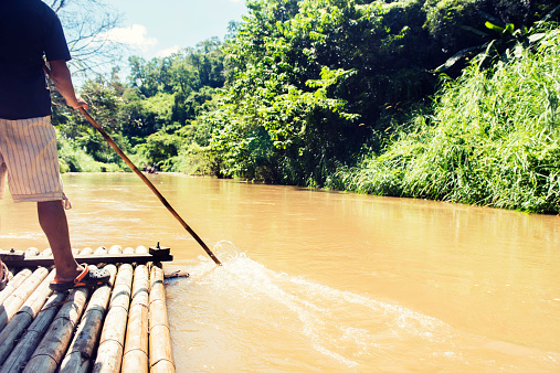 Mae Taeng,  - November 8, 2014: A Thai man guides a bamboo raft on a tour down the Mae Taeng River in the Northern Province of Chiang Mai, Thailand.