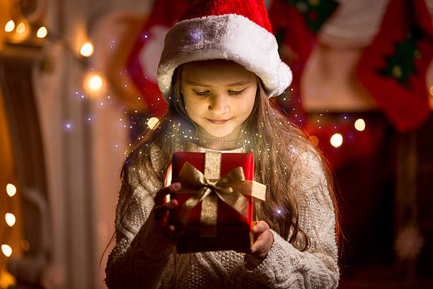 istock cute girl looking inside of glowing Christmas present box 526443873