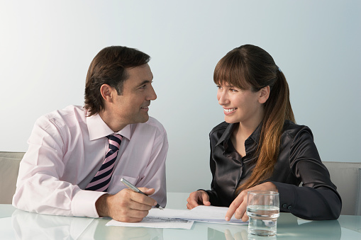 Happy businessman and businesswoman looking at each other while sitting at desk in office