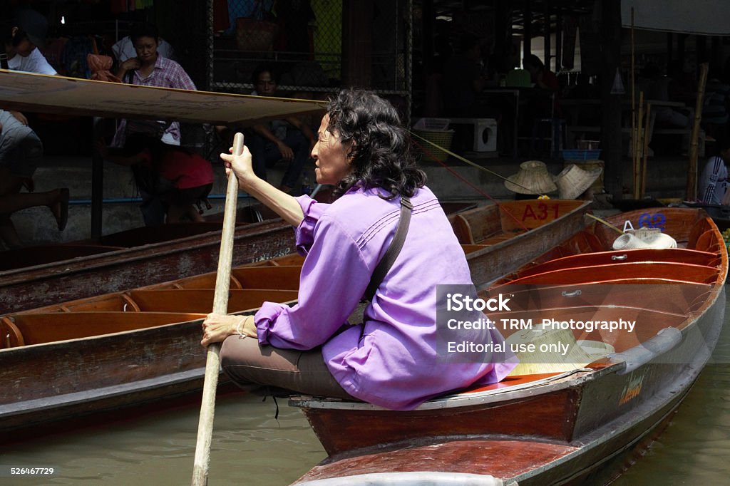 Market Trader At Damnoen Saduak Floating Market Damnoen Saduak, Thailand – March 22, 2014 : A female market trader gazes as she paddles through the Damnoen Saduak floating market.  Active Seniors Stock Photo