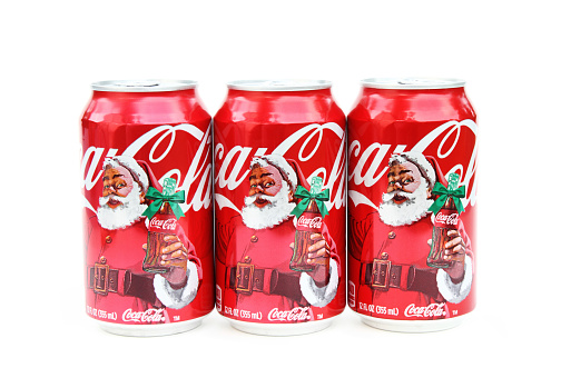 West Palm Beach, USA - December 2, 2014: Three Coca Cola cans showing a Christmas theme of Santa Claus holding a classic Coca Cola bottle with a green ribbon.