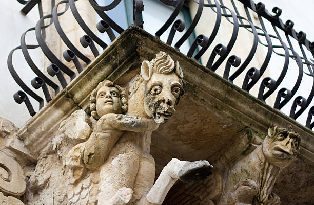 An ornate carved Late Baroque balcony in Scicli, Sicily (Italy). The sculptures date from the 1700s; one appears to be Pegasus with a cherub. The town of Scicli is a UNESCO World Heritage site, part of the Val di Noto group.