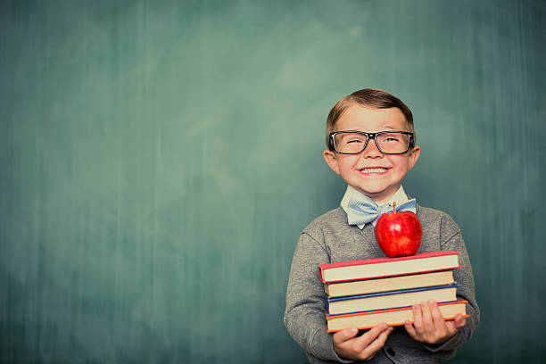 Young Boy Student Dressed as Nerd Holding Books A young and vintage student is ready to learn at school. First, he will give his teacher an apple. school children photos stock pictures, royalty-free photos & images