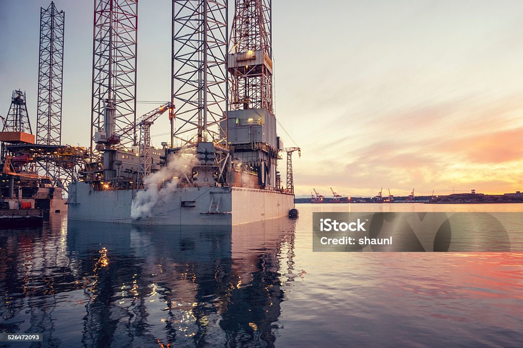 Oil Rigs at Sunset A wide angle view of two offshore drilling platforms anchored in a still harbour. Anchored Stock Photo