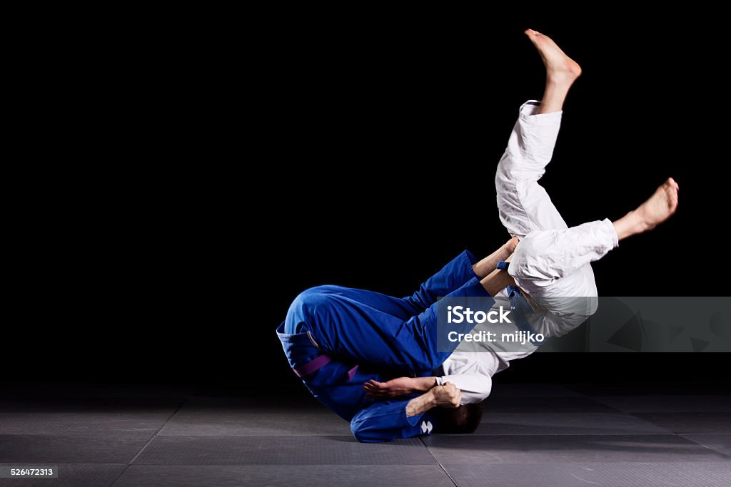 Brazilian jiu-jitsu martial arts Two jiujitsu wrestlers sparring in combat during the sport training. One fighter is throwing the other up over his head.  Jujitsu Stock Photo