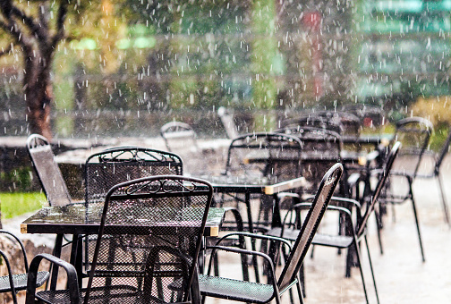 Summer rain falling on outdoor restaurant tables