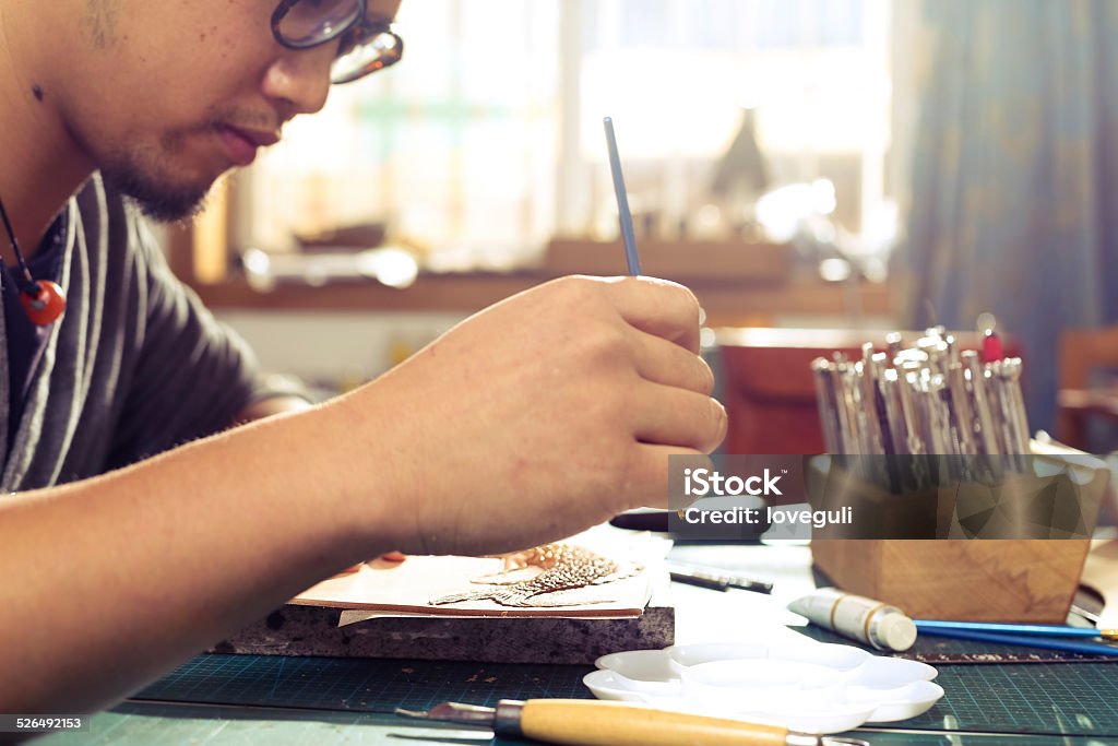 leatherworker painting fish pattern on leather Chinese traditional leatherworker painting fish pattern on the leather Adult Stock Photo