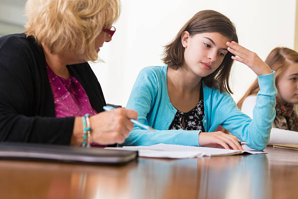 Teacher talking to upset student during detention in school Teacher talking to upset student during detention in school boring homework twelve stock pictures, royalty-free photos & images