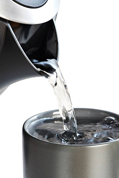 istock Modern kettle pouring water into cup isolated on white 526496799
