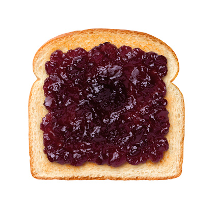Aerial view of a single slice of Toast with grape jelly, or jam. Jelly is a sweet elastic spread made from fruit juice and sugar boiled to a thick consistency. The subject is isolated on a white background.