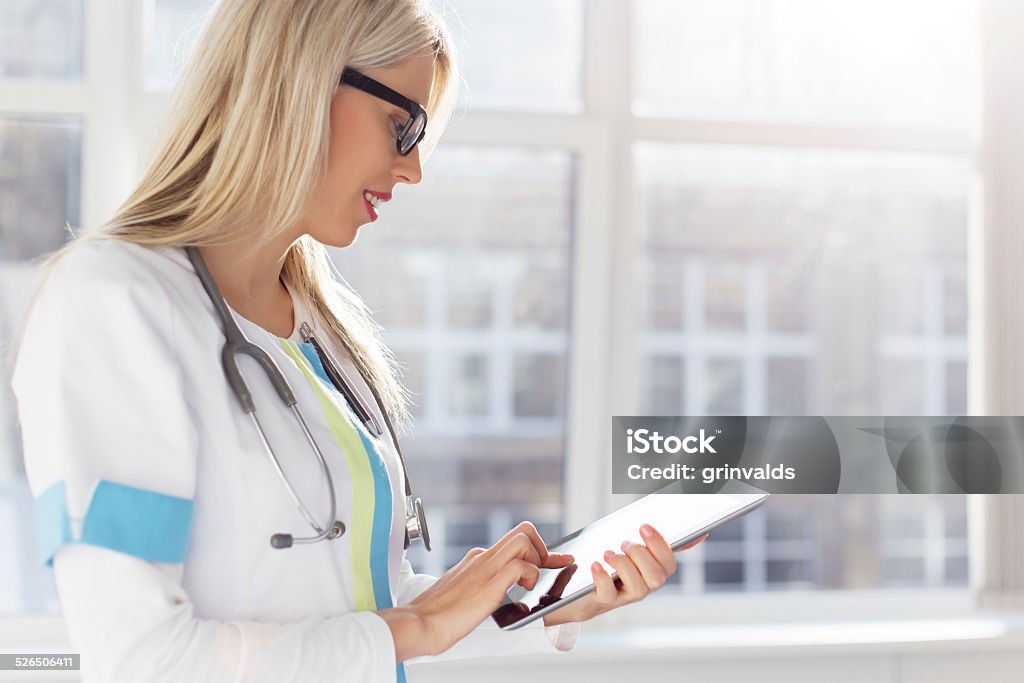 Medico Esaminando la cartella clinica del paziente per computer tablet - Foto stock royalty-free di Adulto