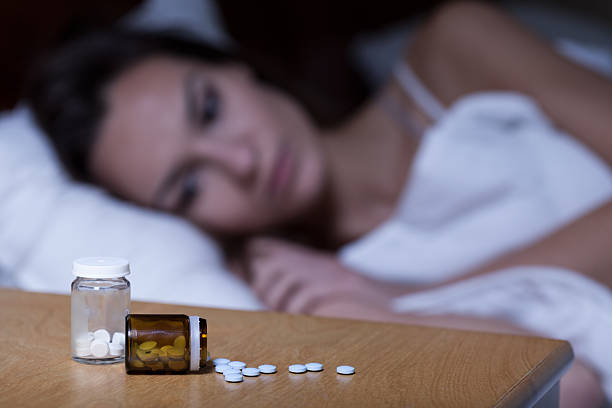 Sleeping pills Woman lying in bed, taking sleeping pills sleeping pill stock pictures, royalty-free photos & images