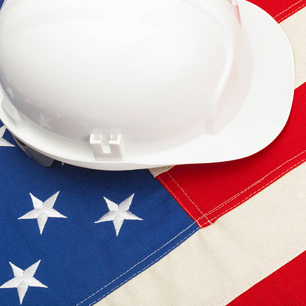 istock White construction helmet laying over US flag 526508157
