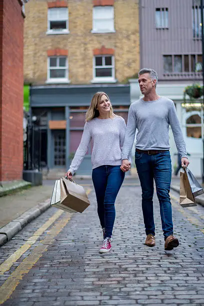 Shopping couple walking outdoors holding bags