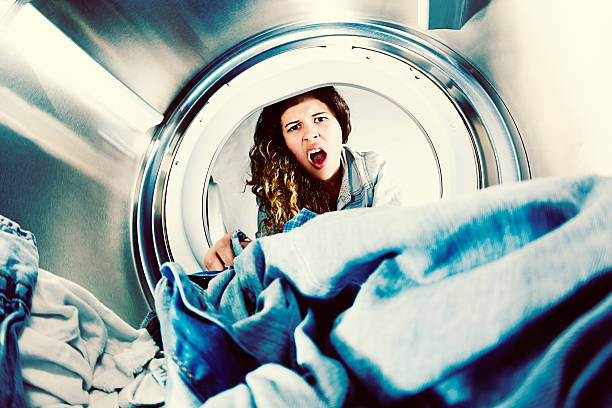 istock Horrified young woman grimaces at laundry in clothes drier 526509453