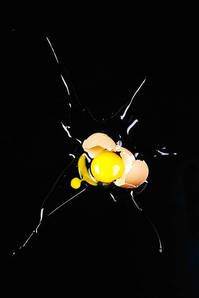 Overhead view of single smashed egg splattered on black perspex Dramatic high-angle  view of one broken egg on black perspex. Copy space at the top.. perspex stock pictures, royalty-free photos & images