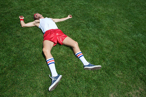 Exhausted Man Collapsed from Too Much Exercise Exhausted man collapsed on the grass from too much exercise too thin stock pictures, royalty-free photos & images
