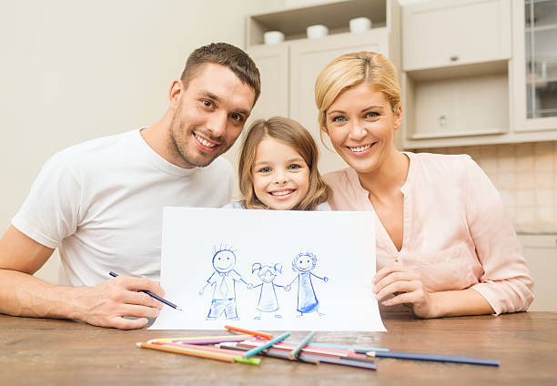 Photo of child's drawing with colored pencils. Picture shows family. Mom, dad, boy, girl, dog are walking together. Mom of African American appearance. Dad is white. Pencils around. White background.