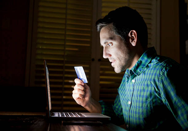 Credit Card Online Laptop Shopper Impulsive buyer on a laptop with a credit card late at night. Names/numbers on credit card removed/altered. free bet stock pictures, royalty-free photos & images