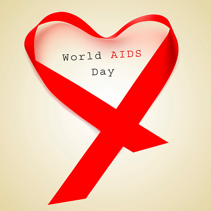 a red ribbon forming a heart and the text world AIDS day on a beige background