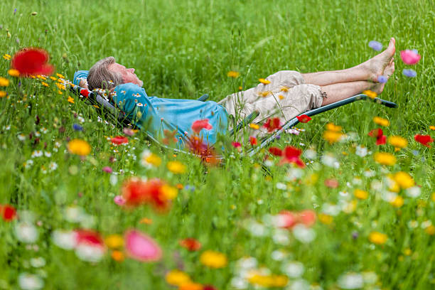 Mindful mature woman meditating by the water, lying down, feeling connected to the earth and nature