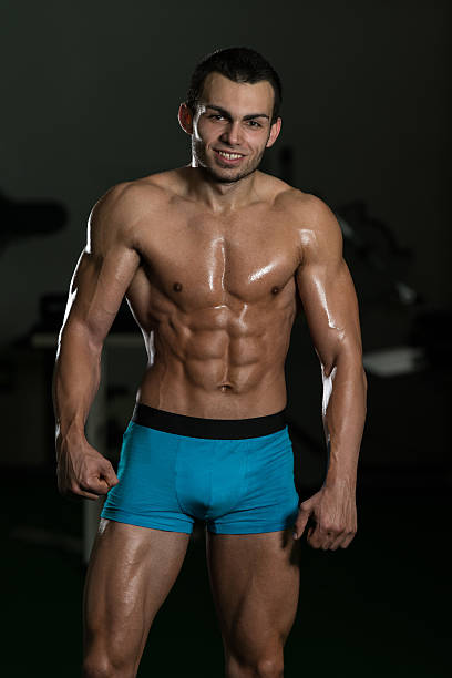 Muscular build. Male beauty portrait of  of a handsome man with beard. Modern sport outfit. Gray background.