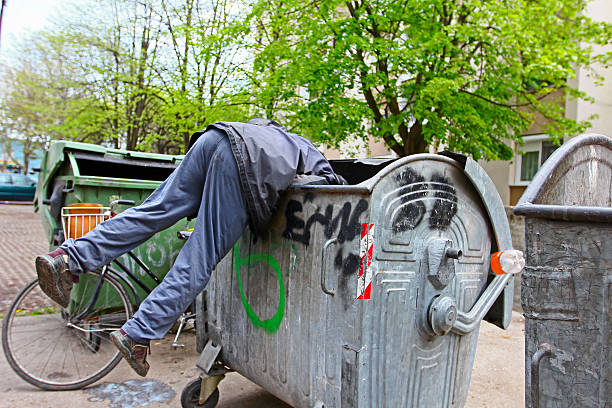 Urban Poverty Homeless man is search for food in garbage industrial garbage bin photos stock pictures, royalty-free photos & images