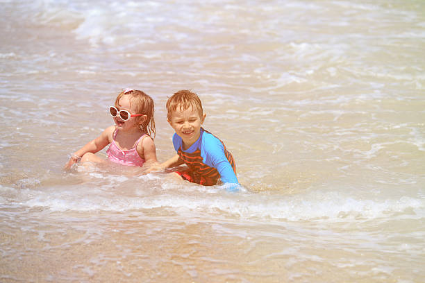 istock happy kids play with waves on beach 526538332