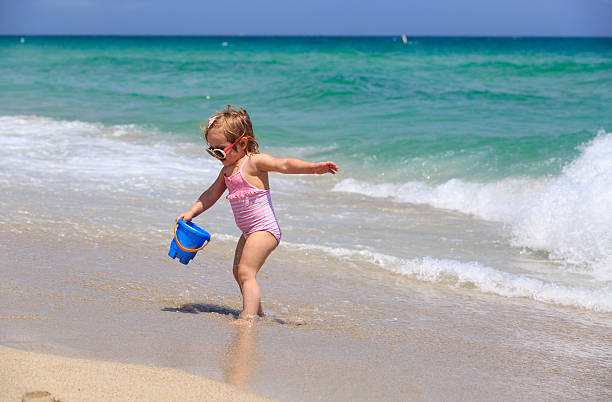 istock cute little girl play with water on beach 526538584