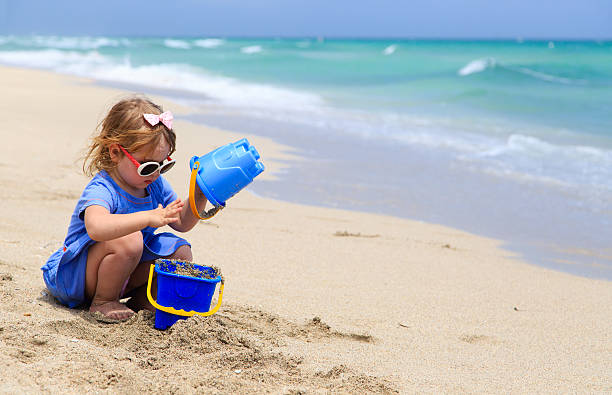istock little girl play with sand on beach 526538712