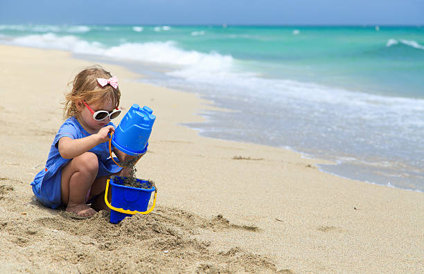 istock little girl play with sand on beach 526538734