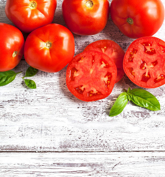 istock Fresh tomatoes and basil on wooden background 526538994