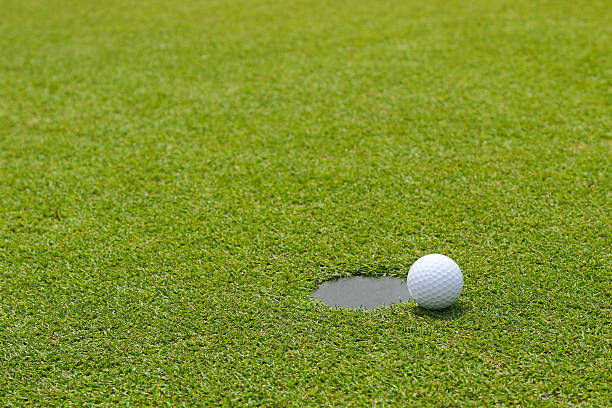 istock Golf ball near putting cup hold at putting green 526547888