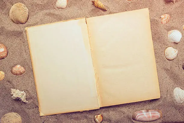 Photo of Top view of open book on sandy beach