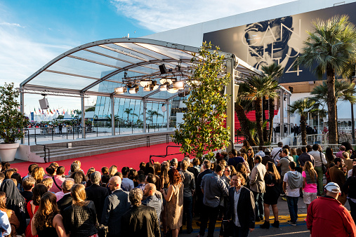 Cannes, France - May 24, 2014: Great Auditorium of the exit door at Cannes in France, the famous red carpeted stairs and crowd of people waiting at the gate output.
