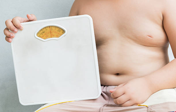 istock obese fat boy holding Weight Scale 526550050