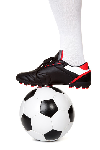 Leg of soccer player with ball on white background