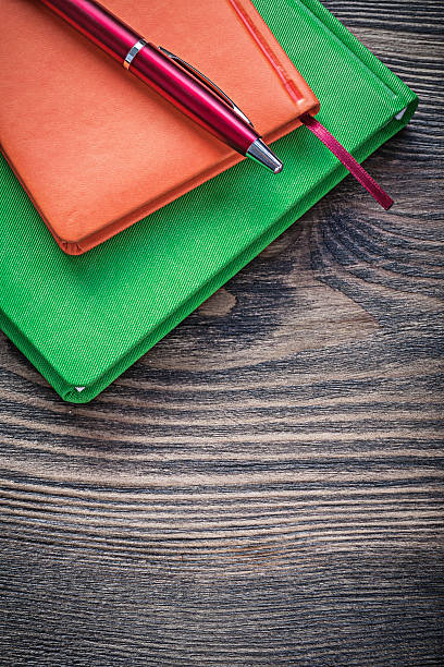 istock Closed note-books ballpoint pen on vintage wood board office 526553256