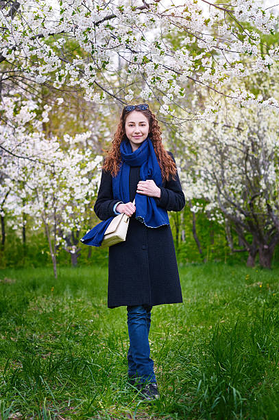 istock young woman in coat walking at blossoming spring cherry garden 526563108