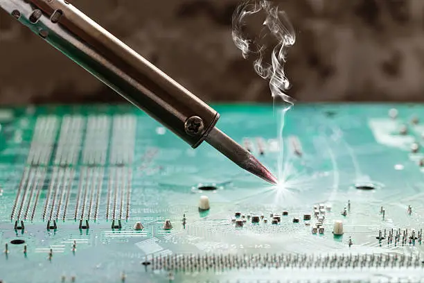 smoking soldering iron on a computer motherboard closeup