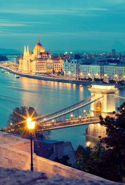 blick auf die kettenbrücke und das parlament in budapest in der dämmerung - chain bridge budapest night bridge stock-fotos und bilder