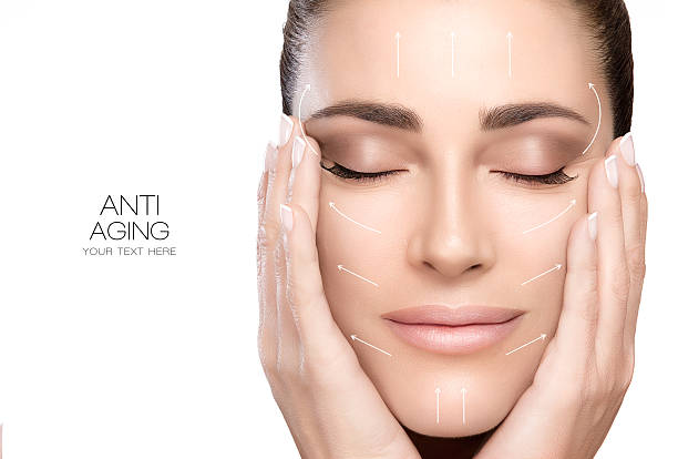 Surgery and Anti Aging Concept. Beauty Face Spa Woman Anti aging treatment and plastic surgery concept. Beautiful young woman with hands on cheeks and eyes closed with a serene expression and white arrows over face. Perfect skin. Portrait isolated on white with copy space for text. facial mask beauty product stock pictures, royalty-free photos & images