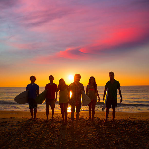 istock Surfers boys and girls group walking on beach 526568897
