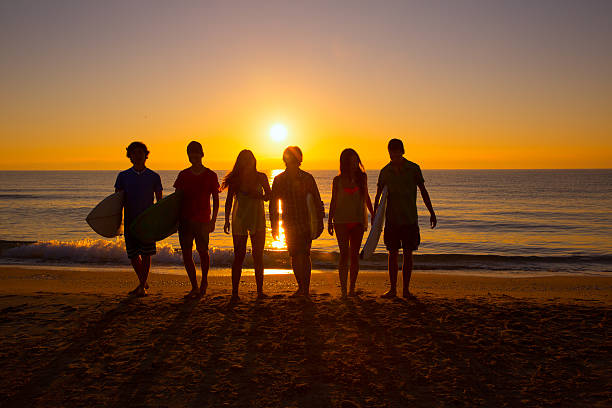istock Surfers boys and girls group walking on beach 526568899