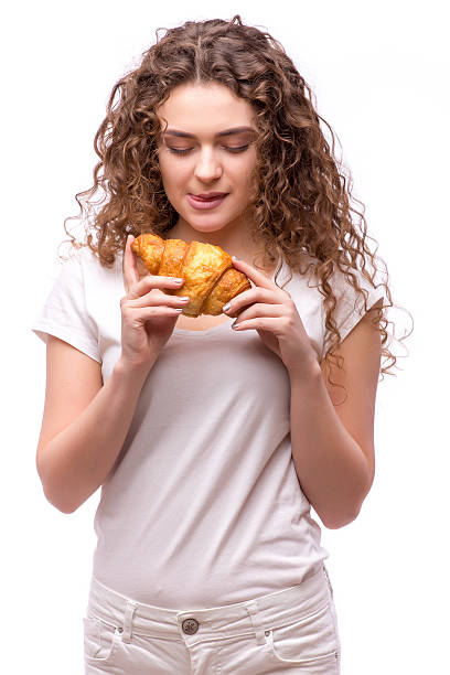 istock Curly woman eating a croissant on isolated background 526568934