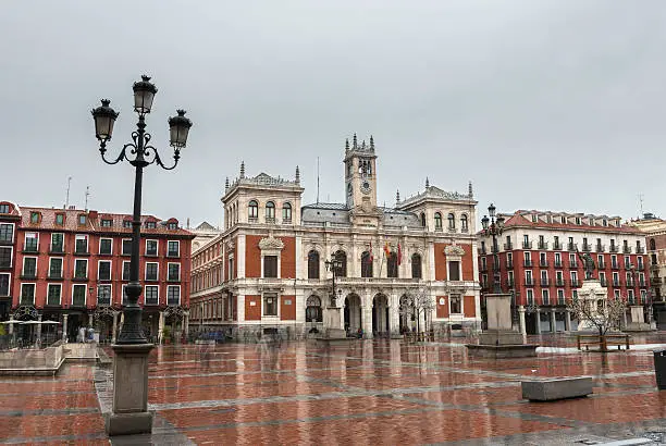Wide-angle view of the main square (Plaza Mayor) in Valladolid on a rainy Autumn morning, with the City Hall already decorated with Christmas lights in the background. Composition of several pictures.